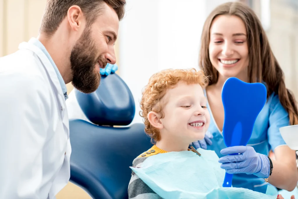 Young boy smiling at a dental visit with his mother