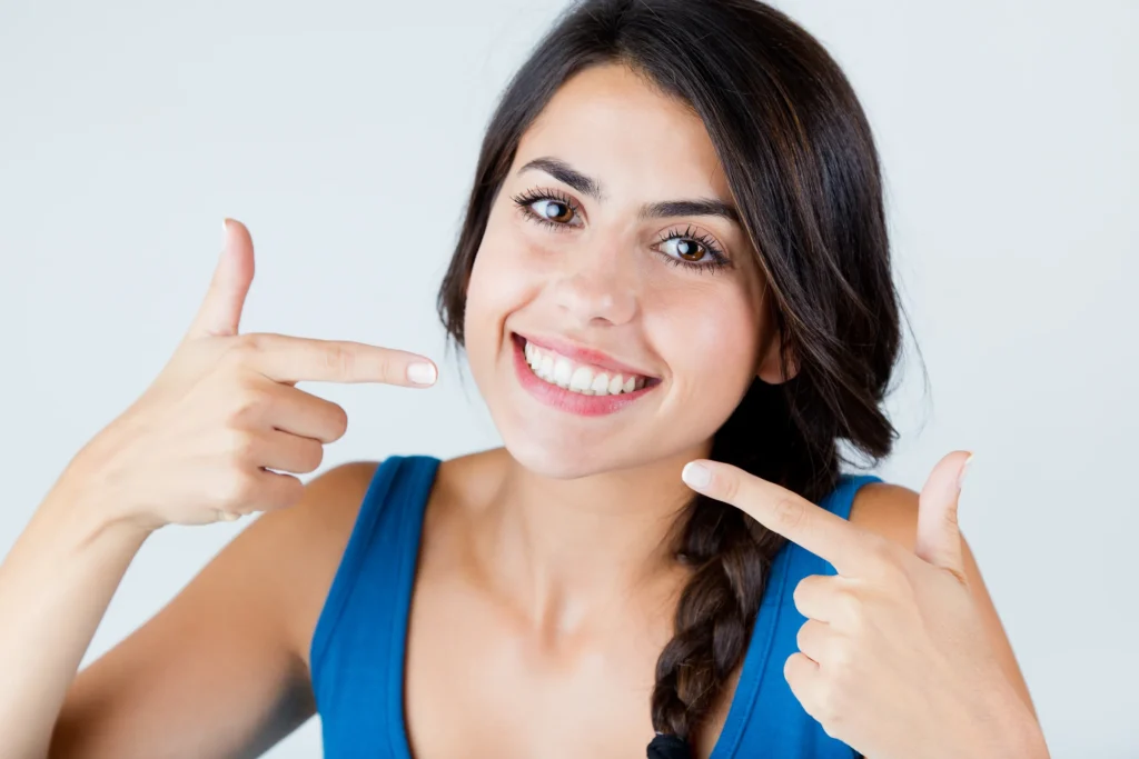 Smiling woman pointing to her white teeth